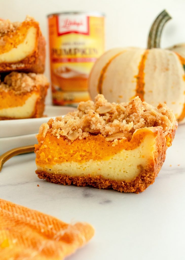 layered pumpkin cheesecake bar with streusel topping and graham cracker crust