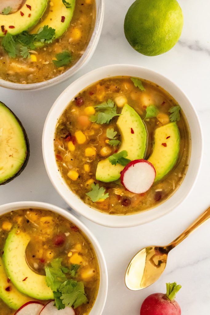 vegan roasted tomatillo soup with sliced avocado on top